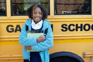 Child standing in front of a school bus