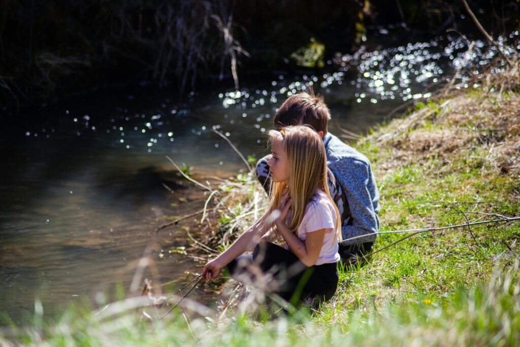Two children enjoying a peaceful moment by a riverbank in spring