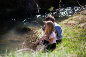 Two children enjoying a peaceful moment by a riverbank in spring